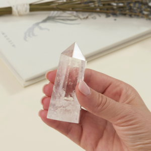 a woman's hand holding a wholesale clear quartz crystal tower