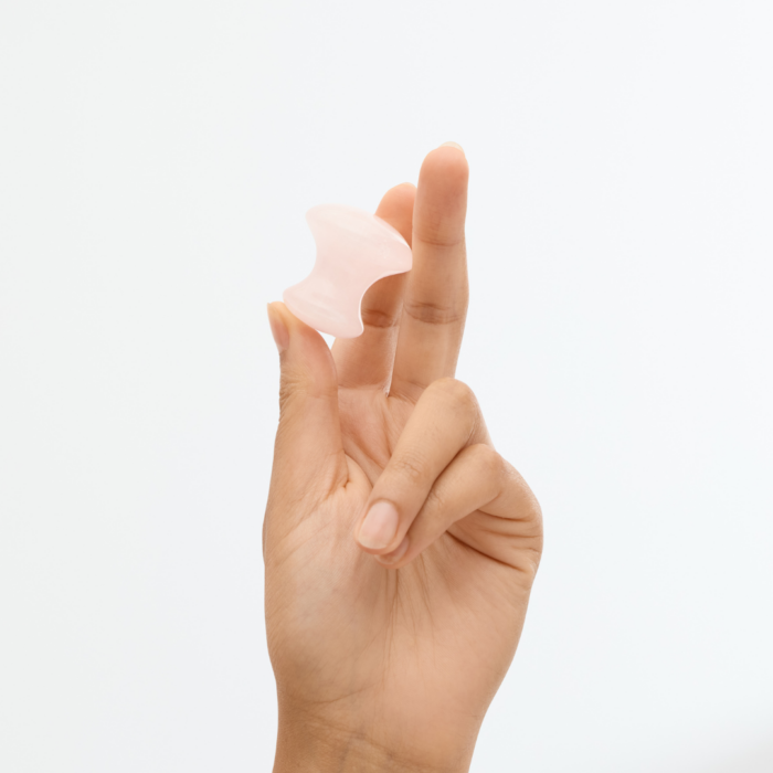 woman's hand holding a whole sale rose quartz gua sha facial massage tool