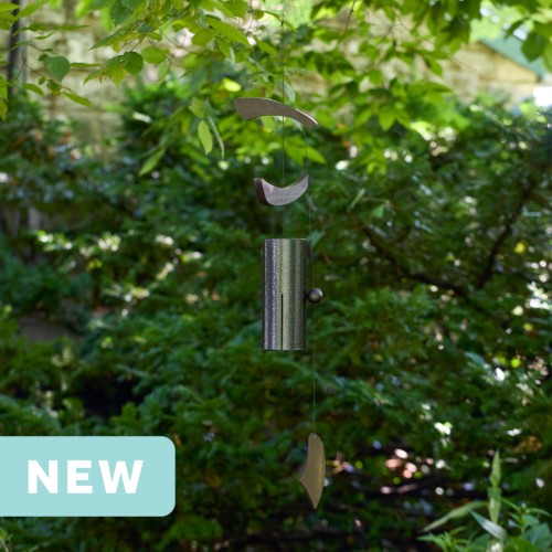 black single bell wind chime with asymmetrical wood wind sails hanging outdoors