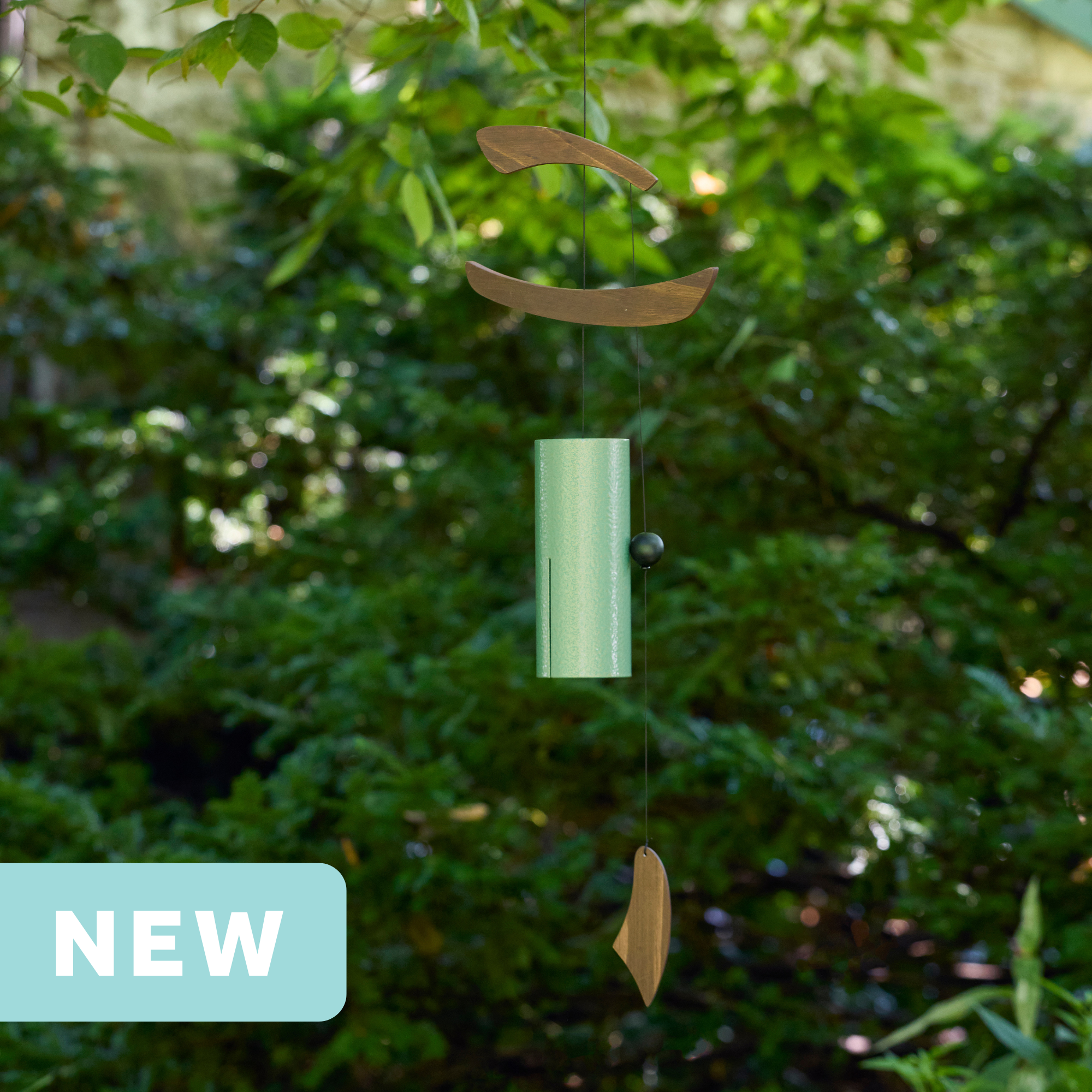 mint and brown single bell wind chime with asymmetrical wood wind sails hanging outdoors