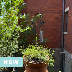 hummingbird mini wind chime in a plant pot on an apartment balcony facing a brick wall