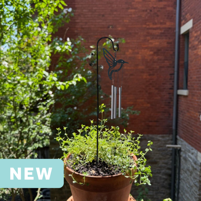 hummingbird mini wind chime in a plant pot on an apartment balcony facing a brick wall