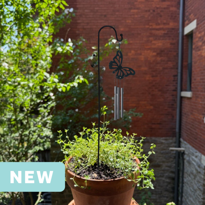 butterfly mini wind chime in a plant pot on an apartment balcony facing a brick wall