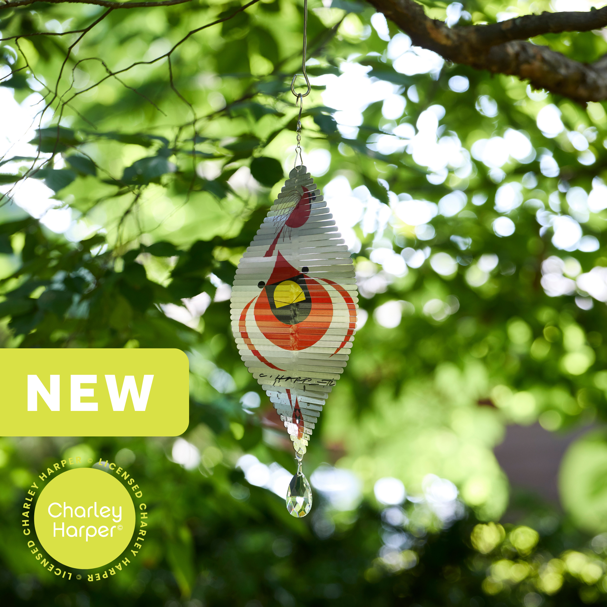 charley harper inspired wind spinner featuring a cardinal on an oblong silver metal spinner hanging in a tree
