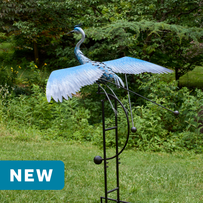 wholesale jumbo garden balance rocker featuring a blue heron with extended wings on a outdoor background with greenery