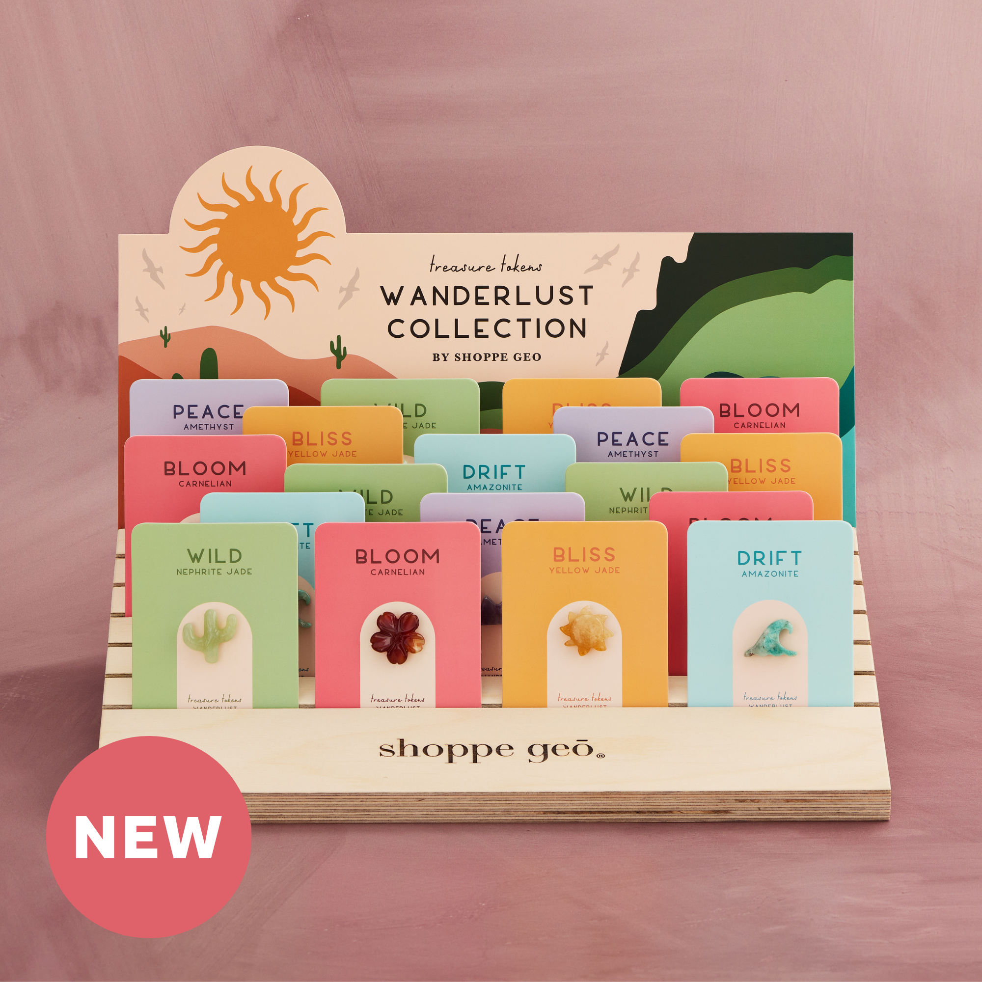 5 wholesale mini carved crystals mounted on backer cards - carnelian hibiscus, nephrite jade cactus, amazonite wave, amethyst mountain, yellow jade sun on a wooden card display with a backer card that reads Treasure Tokens Wanderlust Collection on a mauve background with a pink badge that says NEW