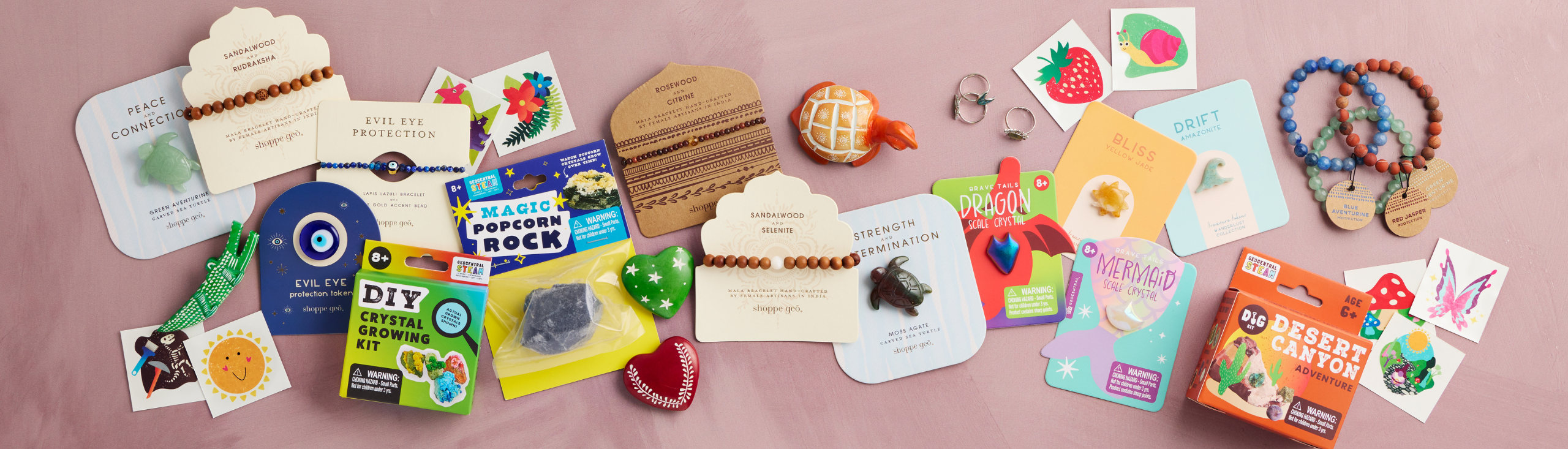 an assortment of new products for 2026 by GeoCentral - jewelry, carved crystals, temporary tattoos, kid's science kits, soapstone figurines
