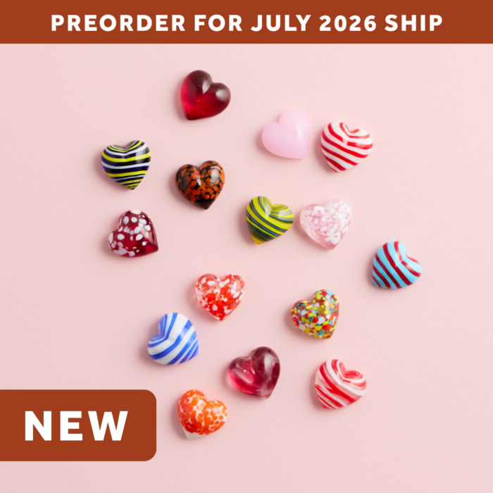 wholesale artisan glass hearts on a pink background. hearts are multicolored with various patterns. text says: preorder for july 2026 ship. NEW.