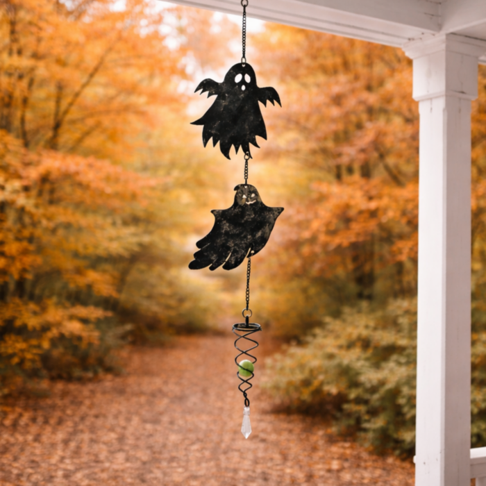 wholesale glow in the dark hanging garden wind spinner featuring 2 friendly ghosts. this is shown hanging on a porch overlooking an autumnal forest with orange leaves