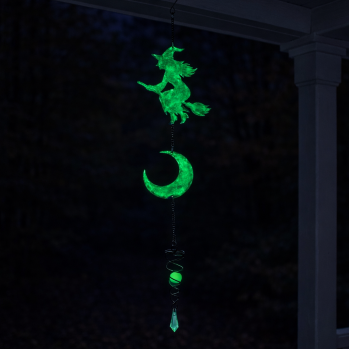 wholesale glow in the dark hanging garden wind spinner featuring a witch on a broomstick and a crescent moon. this is shown glowing in the dark