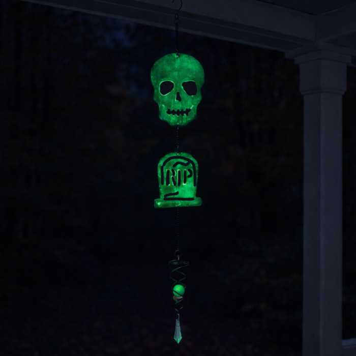 wholesale glow in the dark hanging garden wind spinner featuring a skull and tombstone that shows the letters RIP. this is shown glowing in the dark